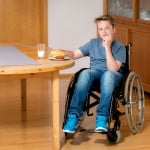 disabled boy in wheelchair is eating